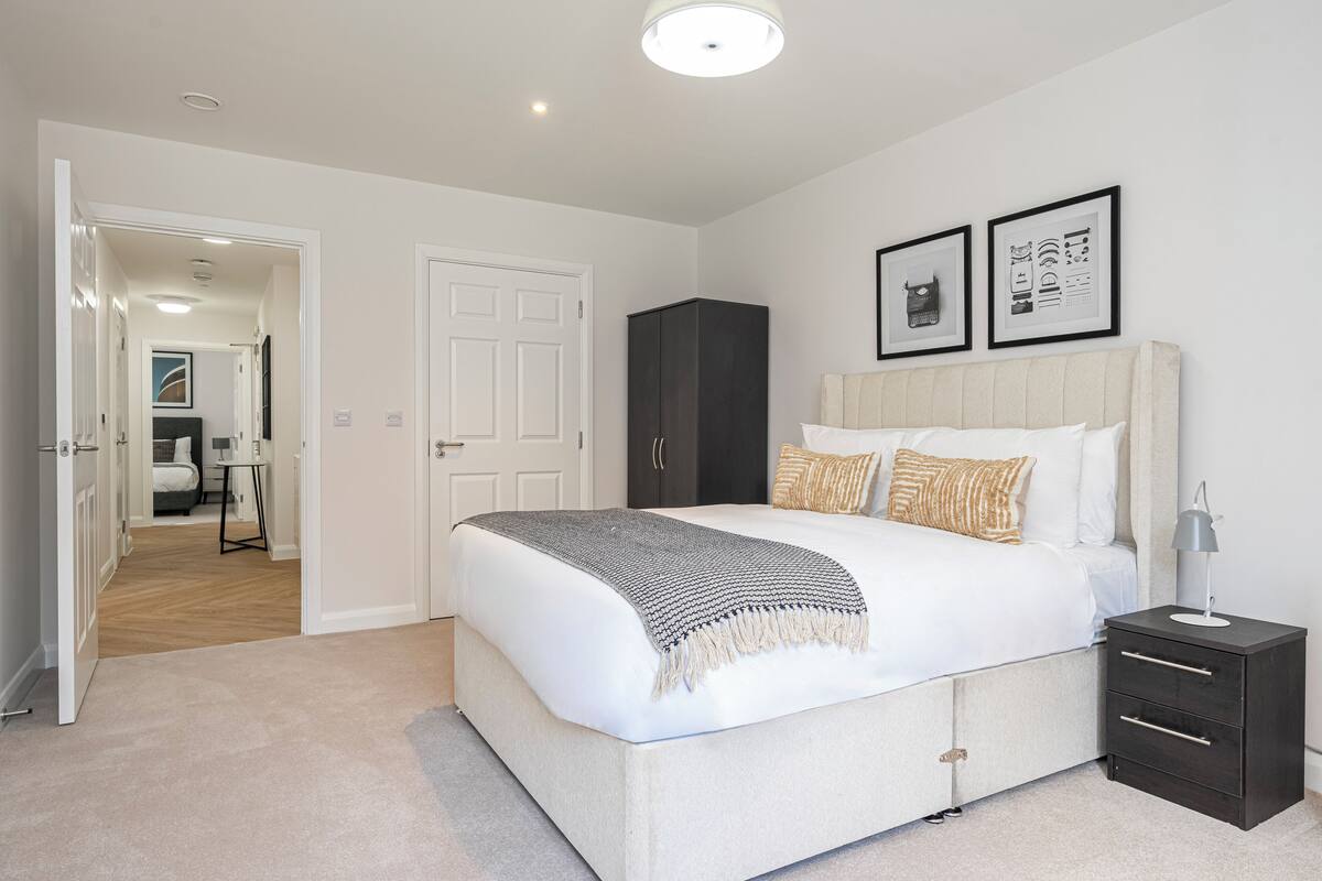 A bedroom with a bed, bedside tables, a wardrobe, and framed pictures on the wall.