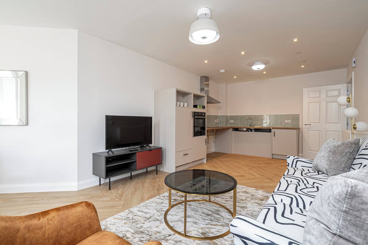 A modern living room with a sofa, a glass coffee table, and a TV.