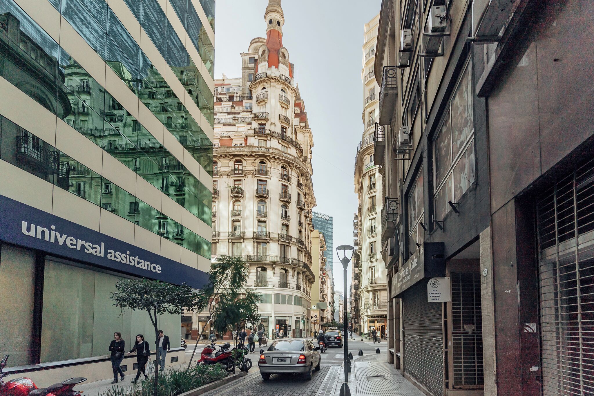 A street view with a building labeled "Universal Assistance" and another building with ornate architecture.