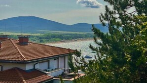 A house with a tiled roof overlooking a river and mountains.