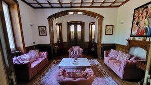 Ein Zimmer mit einem großen Bogenportal, zwei rosa Polsofas, einem zentralen Couchtisch und einem gemusterten Teppich.