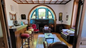 Ein gemütliches Wohnzimmer mit Kamin, Holzmöbeln und Blick durch ein großes, rundes Fenster.