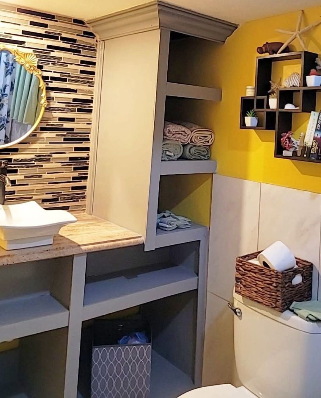 Une salle de bain avec un meuble-lavabo intégré, des étagères pour les serviettes et une décoration en forme d’étoile de mer sur le mur.