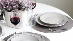 A dining table set with plates, cutlery, and glasses, accompanied by a potted plant. - Modern Room Exarchia Room 4 (Αθήνα)