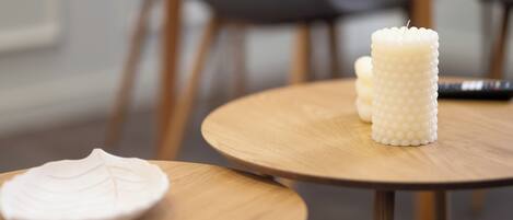 A round wooden table with a white candle and a white ceramic plate.