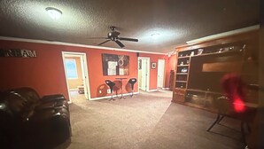 A room with a ceiling fan, a red wall, a door, and a wooden cabinet. - FIFA Ready! Spacious 1800 sqf (Ellenwood)