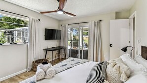A bedroom with a bed, a desk, a TV, and a ceiling fan. - Relaxing Modern Home Sleeps 6/Pool/BBQ/Firepit (Sorrento)