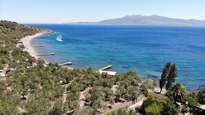 A coastal landscape with a beach, a pier, and a mountainous backdrop.