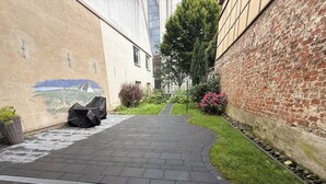 A paved pathway leading to a building with a mural on the left wall. - Stylish apartment right next to the market and town hall (Stralsund)