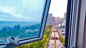A view from a window overlooking a cityscape with a highway, parked cars, and greenery. - Chic 1-bedroom apartment in charming Batumi with AC, WiFi (Batumi)