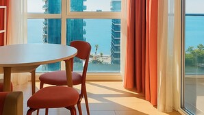 A modern room with a large window, a round table, and red chairs. - Chic 1-bedroom apartment in charming Batumi with AC, WiFi (Batumi)