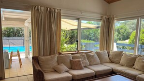 A living room with a sofa, a coffee table, and a view of a swimming pool.