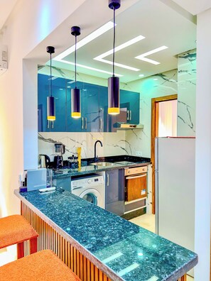 A modern kitchen with a central island, built-in appliances, and pendant lighting.
