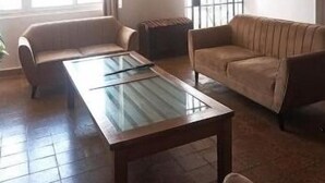 Un salon spacieux avec une table basse au plateau en verre, deux canapés et une grande fenêtre avec des vitres à croisillons.