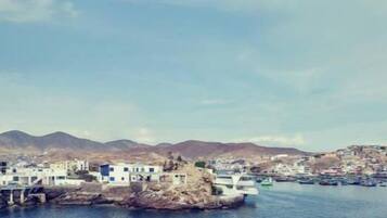 A coastal town with buildings on a rocky outcrop and boats in the water.