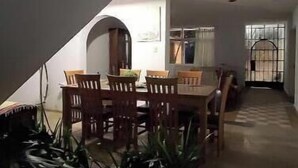 Een eetruimte met een tafel, stoelen, een trap en uitzicht op buiten.
