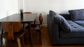 A modern living room with a dark grey sofa, wooden dining table, and matching chairs. - Marble Arch - Central London Apartment - Air Conditioner (London)