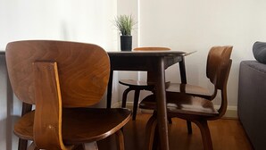 A dining area with a wooden table and four chairs, a small potted plant, and a grey sofa. - Marble Arch - Central London Apartment - Air Conditioner (London)