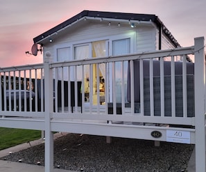 Een wit huis met een omheinde veranda, een schotelantenne en een bord met het nummer 40.