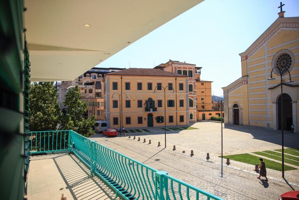 Un patio con barandilla verde, un edificio con cúpula e iglesia con cruz.