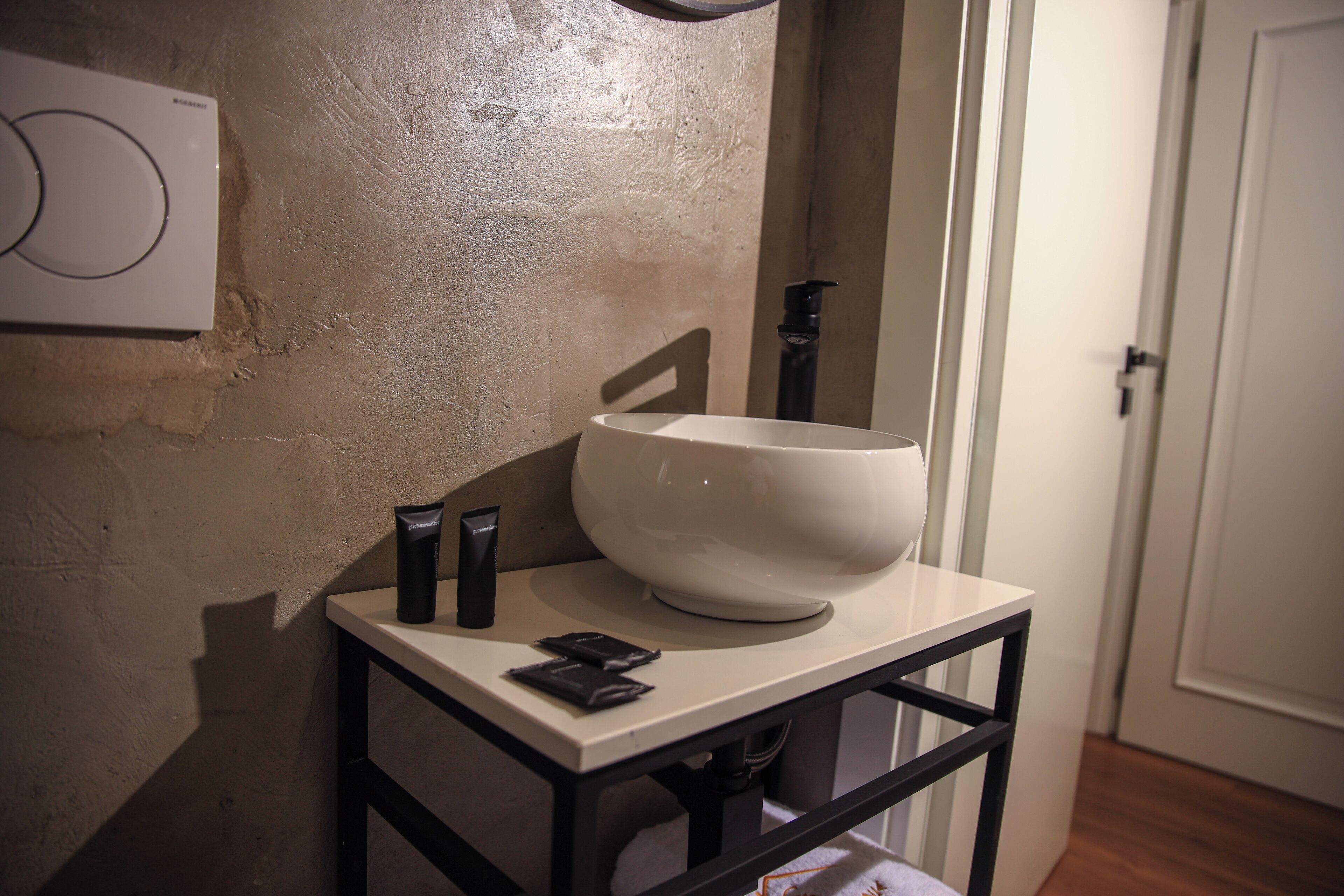A bathroom with a white sink, a black faucet, and a white wall with a circular design.