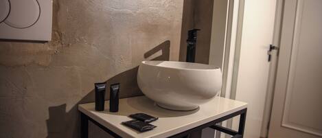 A bathroom with a white sink, a black faucet, and a white wall with a circular design.