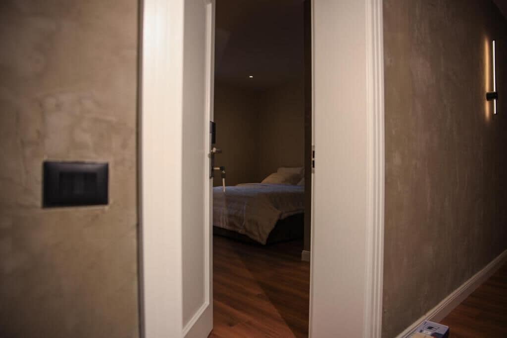 Un pasillo estrecho que lleva a un dormitorio con cama y mesita de noche.