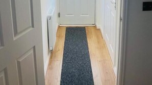Pasillo que conduce a una puerta con un ventanal esmerilado y un buzón pequeño.