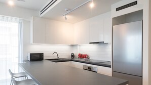 A modern kitchen with a large island, stainless steel appliances, and white cabinetry. - LIV Athinum 1 - Luxury Apartment 2A (Athens)