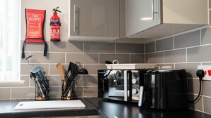 Eine Küche mit einem schwarzen Toaster, einer Branddecke und einem Feuerlöscher an der Wand.