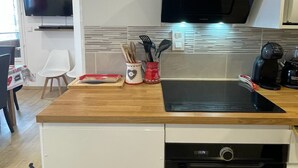 A modern kitchen with a built-in oven, a microwave, and a black range hood. - Fully renovated duplex apartment at the foot of the slopes. (Allos)