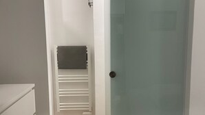 A bedroom with a bed, a white dresser, a closet with a sliding door, and a small shelf with a towel. - Fully renovated duplex apartment at the foot of the slopes. (Allos)