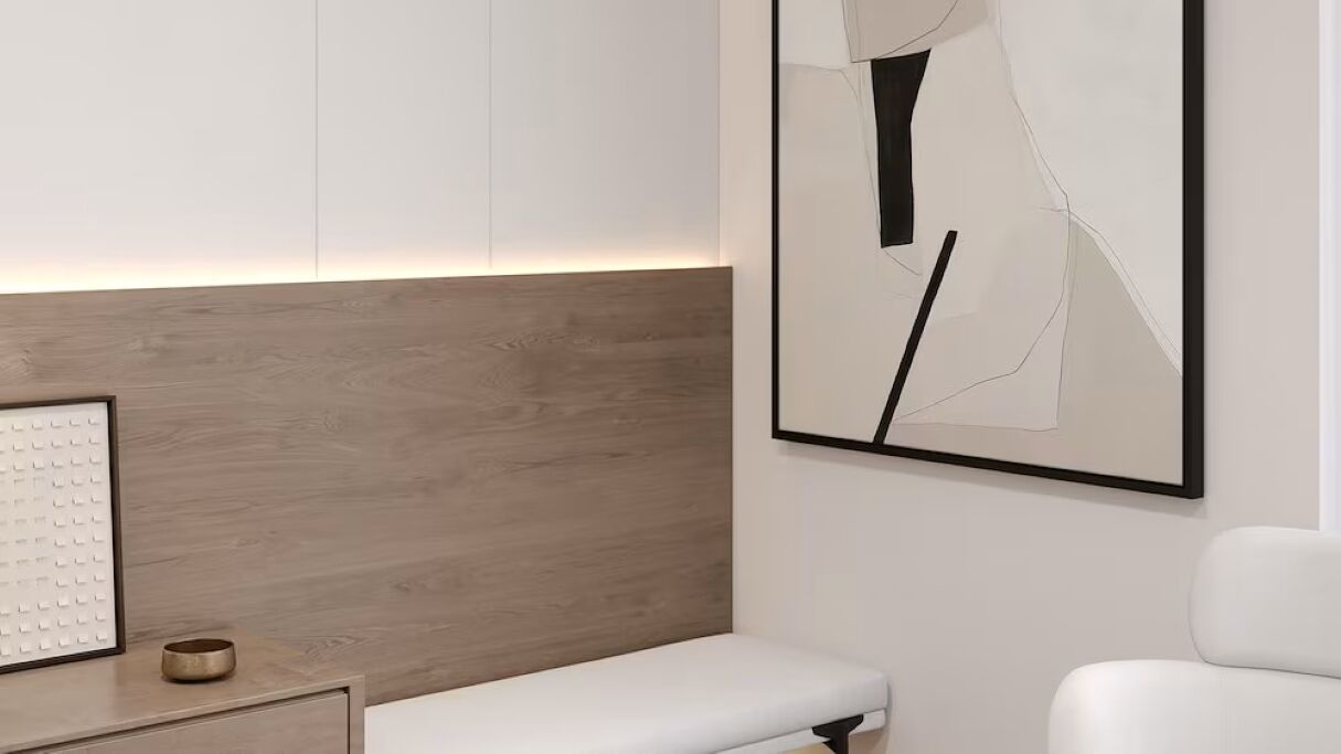 A modern room with a wooden headboard, a white bench, and a framed abstract artwork on the wall.