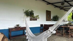 Una habitación con una hamaca, muebles de madera y plantas en macetas.