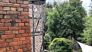 A brick building with a tower in the background, surrounded by trees and a grassy area. - Apartment 7 Lemon (Lüneburg)