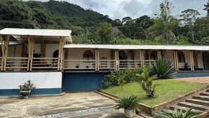 Un edificio con un espacio exterior cubierto, un patio de concreto y un césped con plantas en macetas.
