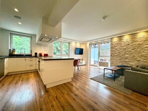 Eine moderne Küche mit einer zentralen Kochinsel, Holzböden und einer Wand mit Steinverkleidung.