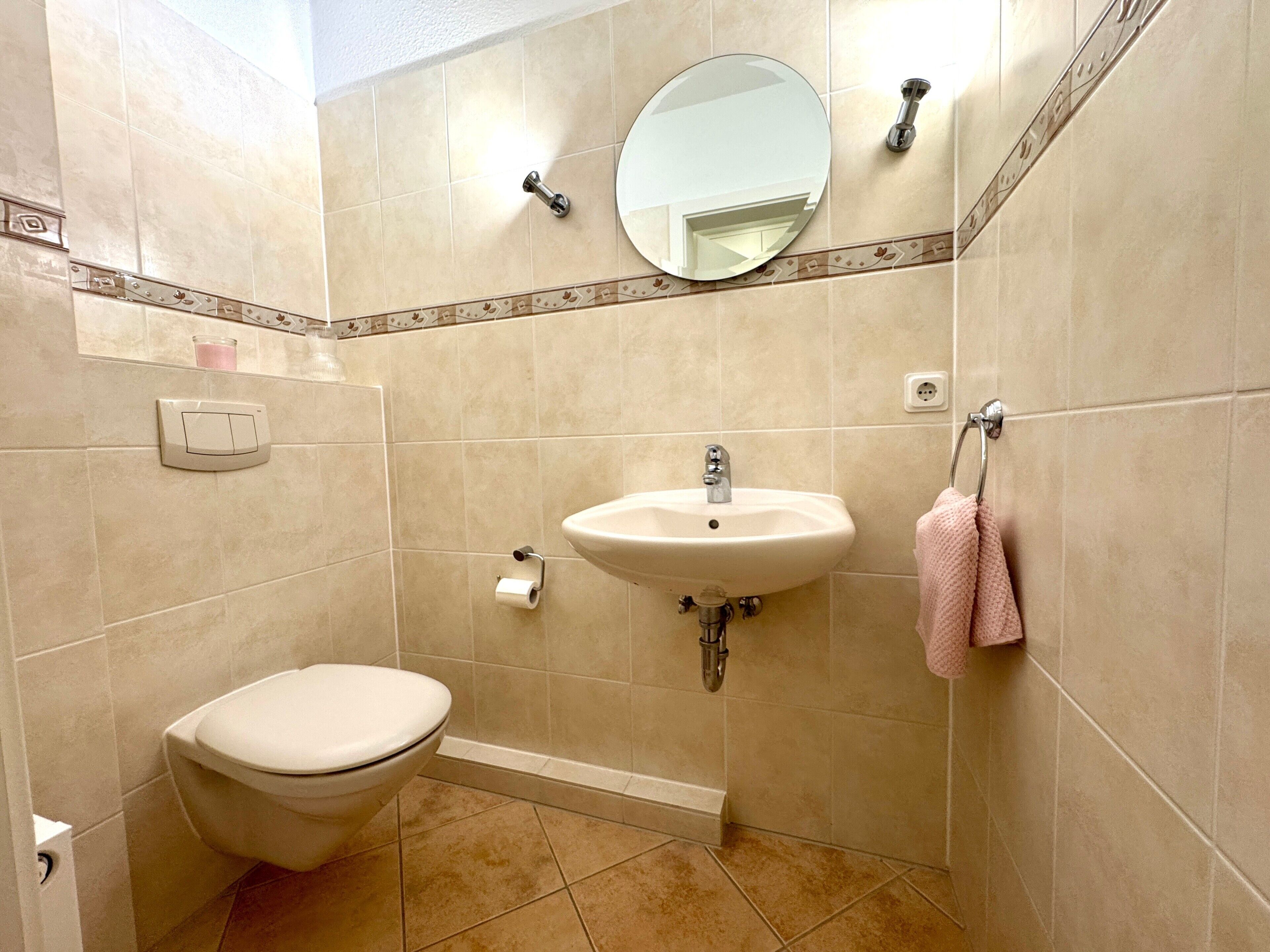 Ein Badezimmer mit Toilette, Waschbecken, Spiegel und Handtuchhalter.