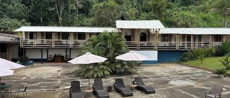 Un hotel con piscina, sillones de descanso y sombrillas.