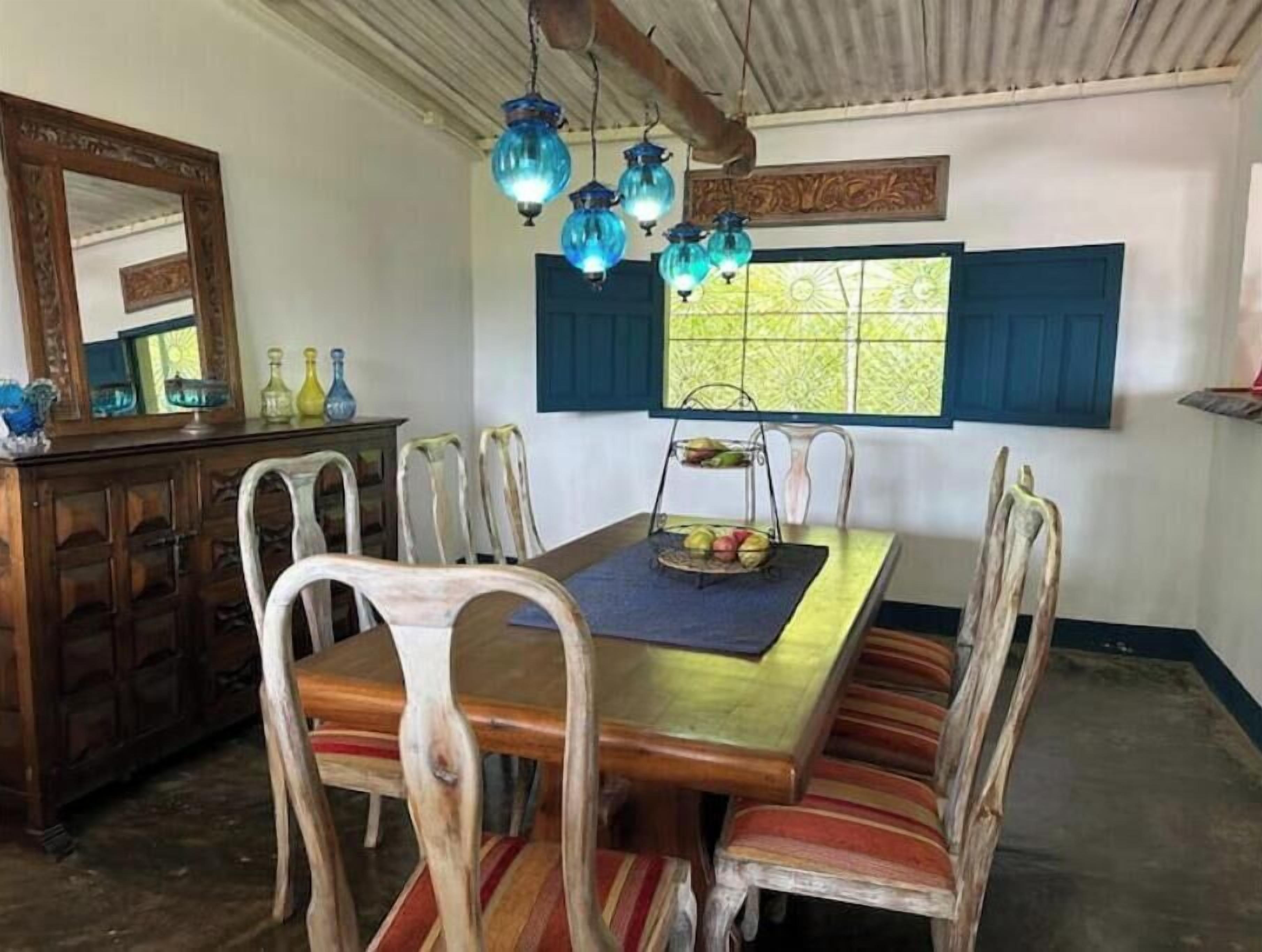 A dining area with a wooden table, striped chairs, and hanging blue lanterns.