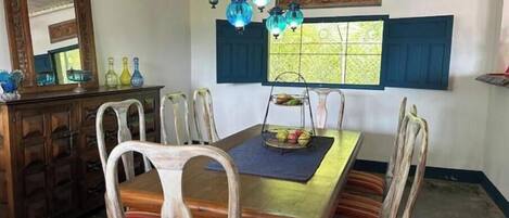 A dining area with a wooden table, striped chairs, and hanging blue lanterns.