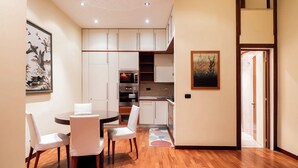 A modern kitchen with white cabinets, a dining area with a round table and chairs, and a wooden floor. - Umbertina Cozy Apartment by Wonderful Italy (Bari)