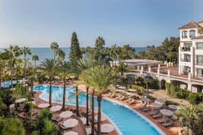 Un resort con una grande piscina, palme e vista sull'oceano.