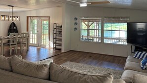 A spacious living room with a large sofa, a dining area with a table and chairs, a TV, and a ceiling fan. - WATERFRONT with private dock ,boat ramp, paddle boats and Kayaks!! (Many)