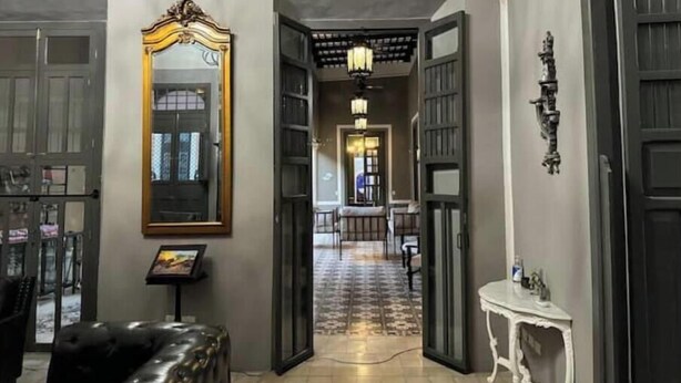 A hallway with open doors leading to a dining area, a large mirror, and a small table with a picture frame. - Casa Agape in Downtown Mérida (Mérida)
