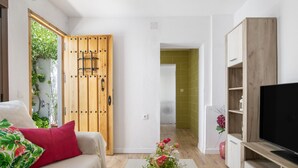 Een moderne woonkamer met een bank, een televisie, houten kasten en een gang met groene tegels.