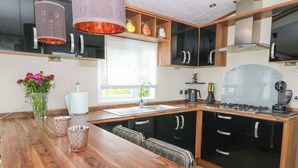A modern kitchen with a wooden countertop, black cabinets, and a built-in stove. - Ty Seren (New Quay)
