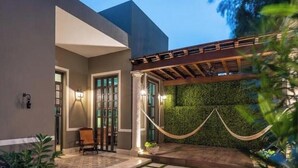 A modern building with a covered entrance, a hammock, and a green wall.