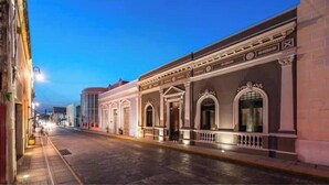 A street view of a historic building with classical architecture, including arched windows and decorative moldings.