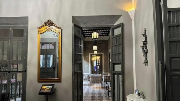 A hallway with open doors leading to a dining area, a large mirror, and a white console table.